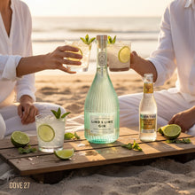 Load image into Gallery viewer, Two people enjoying cocktails with bottles of Lind &amp; Lime Gin and Fever-Tree Tonic Water on a beach.