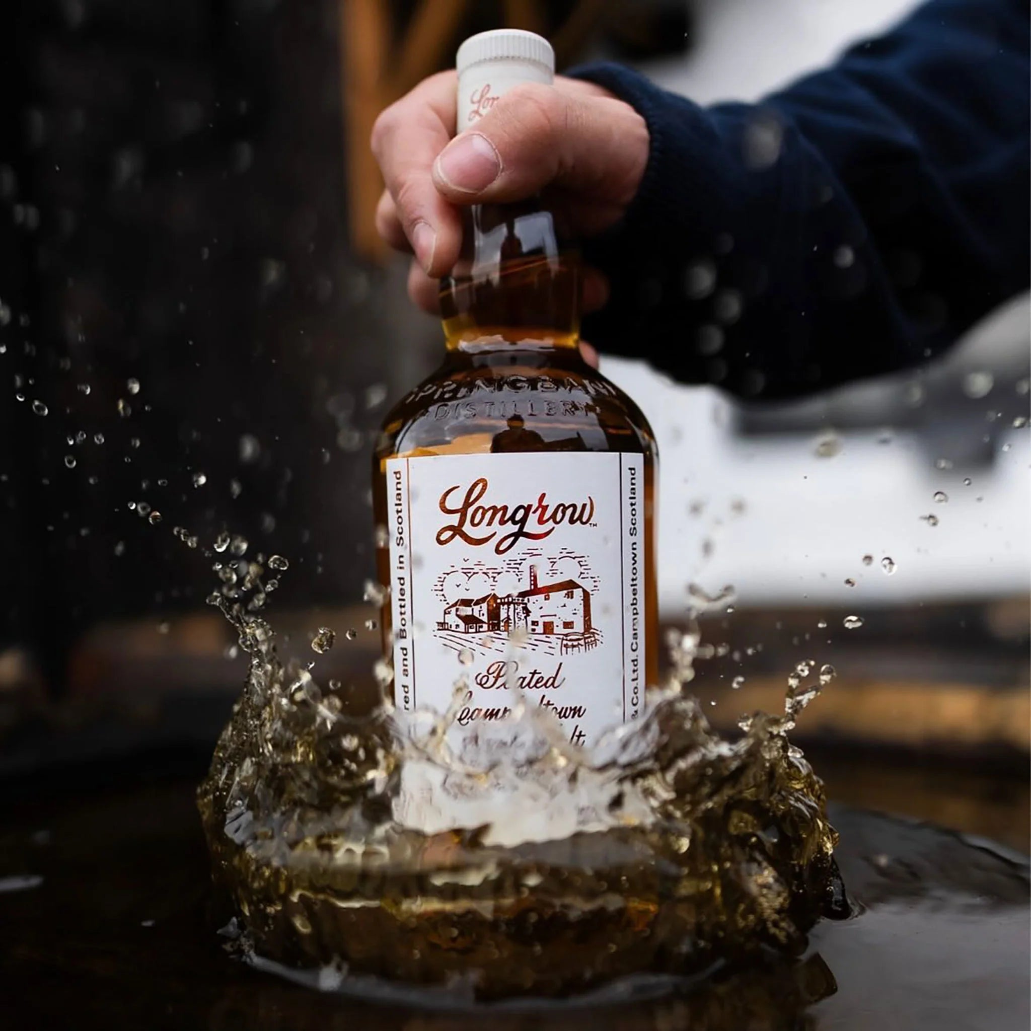 Load image into Gallery viewer, Bottle of Longrow Peated Single Malt Scotch Whisky being splashed into water with a blurred background