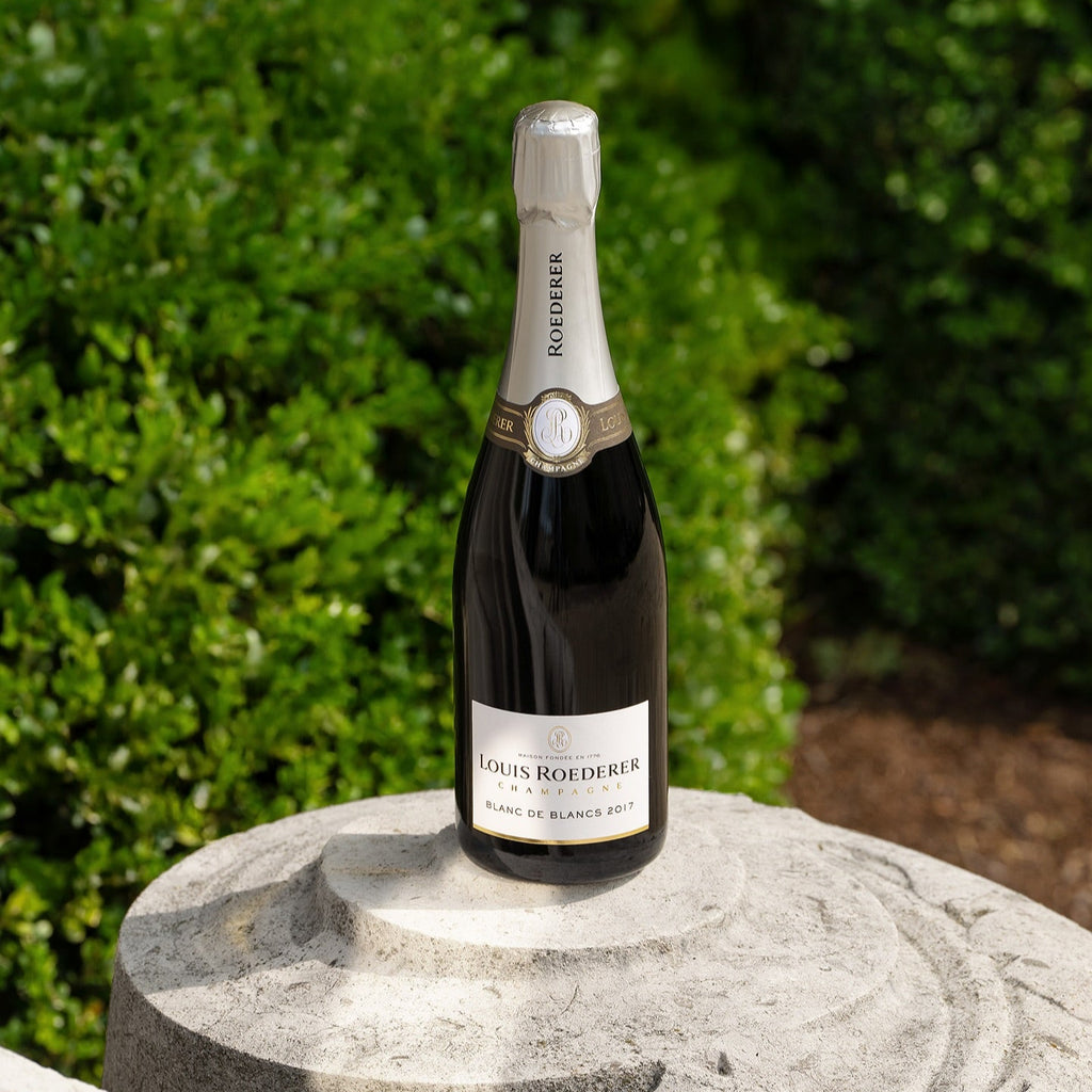 Bottle of Louis Roederer champagne on a stone pedestal with greenery in the background