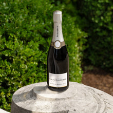 Load image into Gallery viewer, Bottle of Louis Roederer champagne on a stone pedestal with greenery in the background