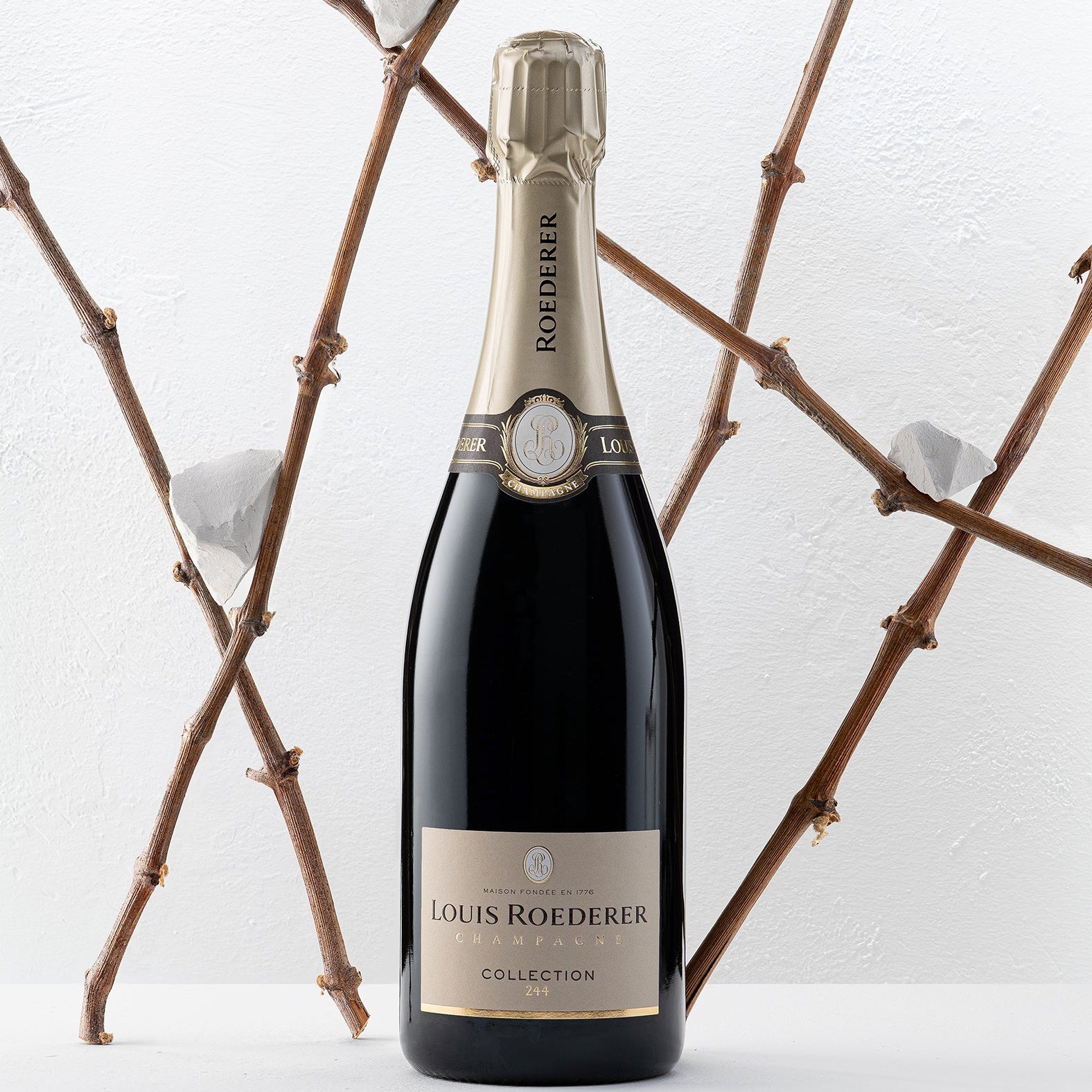 Load image into Gallery viewer, Louis Roederer champagne bottle with decorative branches in the background