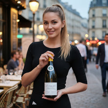 Load image into Gallery viewer, Woman holding a bottle of Louis Latour Bourgogne Chardonnay wine in an outdoor setting with blurred background
