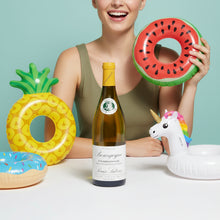 Load image into Gallery viewer, Woman holding inflatable watermelon, pineapple, and donut rings with a bottle of Louis Latour Bourgogne Chardonnay wine and unicorn toy.