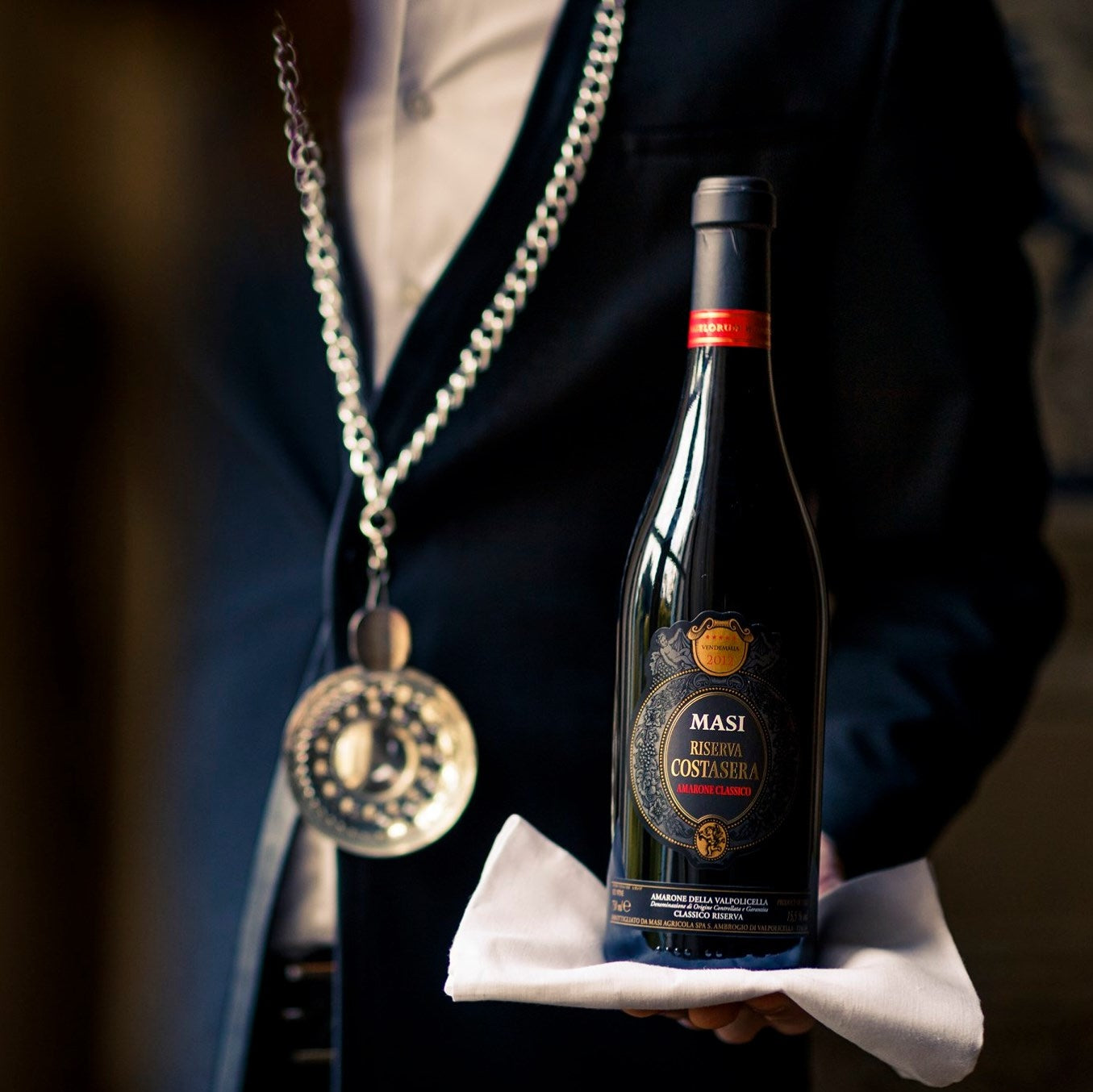 Load image into Gallery viewer, A waiter carrying a bottle of MASI Amarone Riserva di Costasera Classico wine