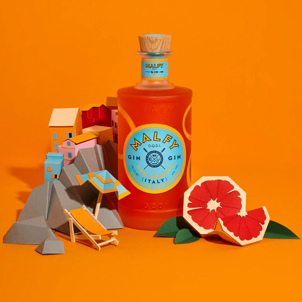 Load image into Gallery viewer, Bottle of Malfy Arancia Orange gin with a label on an orange background, accompanied by a grapefruit and miniature structures.
