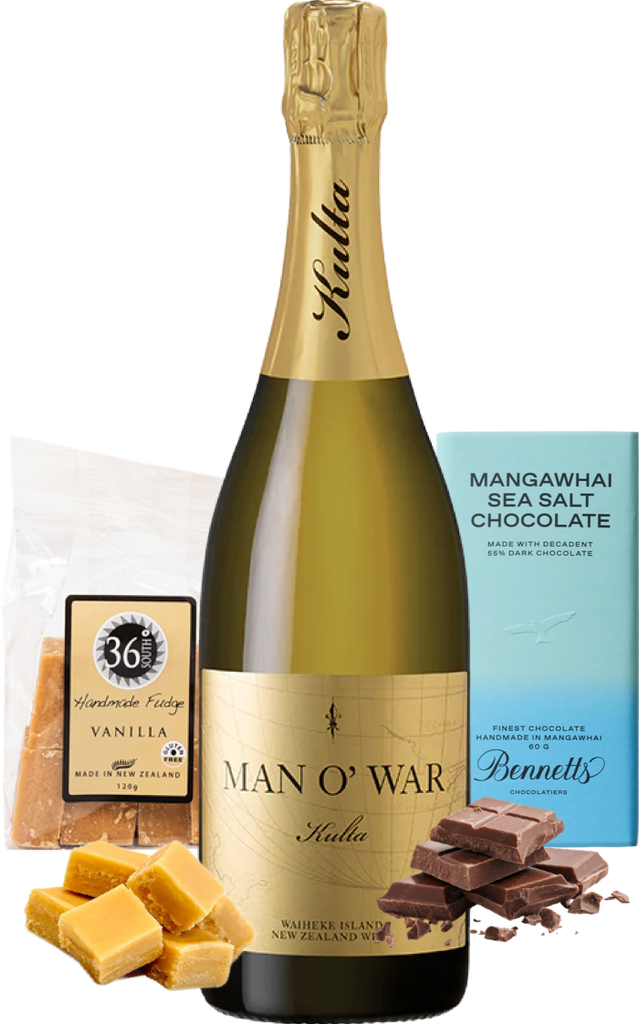 A Man O’ War Kulta Tulia Blanc de Blanc sparkling wine bottle centred on a white background, surrounded by gift items including a bag of 36 Degrees vanilla handcrafted fudge, a box of Bennett's Mangawhai sea salt chocolate, and pieces of vanilla fudge and dark chocolate.