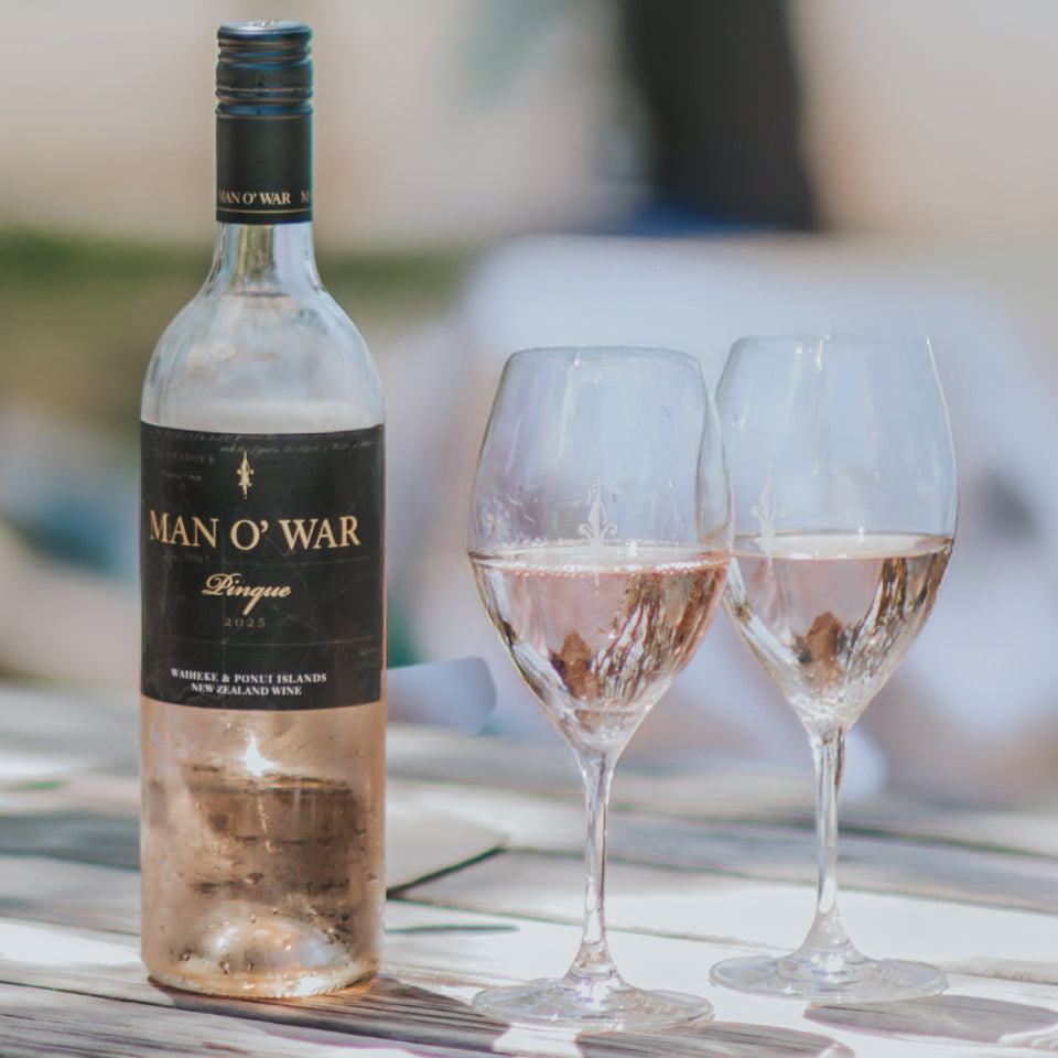 Load image into Gallery viewer, Bottle of Man O' War Rosé wine with two glasses on a wooden surface outdoors.