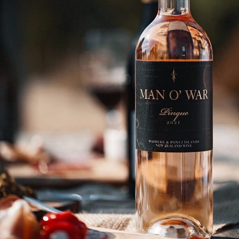 Load image into Gallery viewer, A bottle of Man O' War rose on a table with a blurry background