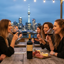 Load image into Gallery viewer, Group of women enjoying a bottle of Man O&#39; War Kulta Tytti Red Blend wine and food at a rooftop bar with city skyline in the background