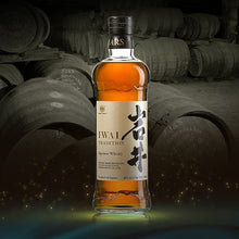 Load image into Gallery viewer, Bottle of Iwai Tradition Japanese whisky with barrels in the background.