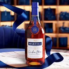 Load image into Gallery viewer, A bottle of Martell Cordon Bleu Cognac on a marble table with a blue ribbon flying around the bottle