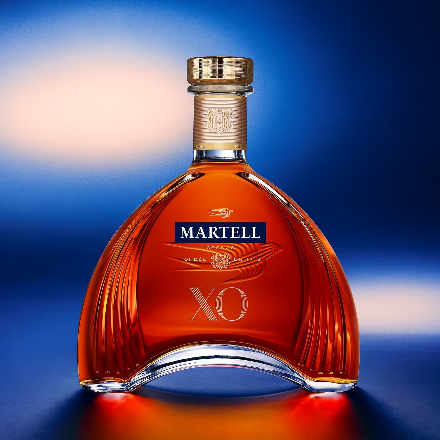 Load image into Gallery viewer, A Martell XO Cognac bottle on blue background