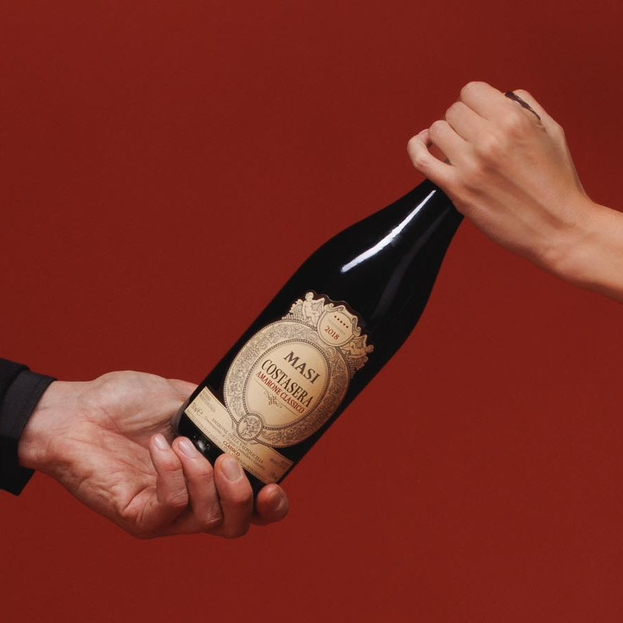 Load image into Gallery viewer, two hands holding a bottle of Masi Costasera Amarone Classico red wine