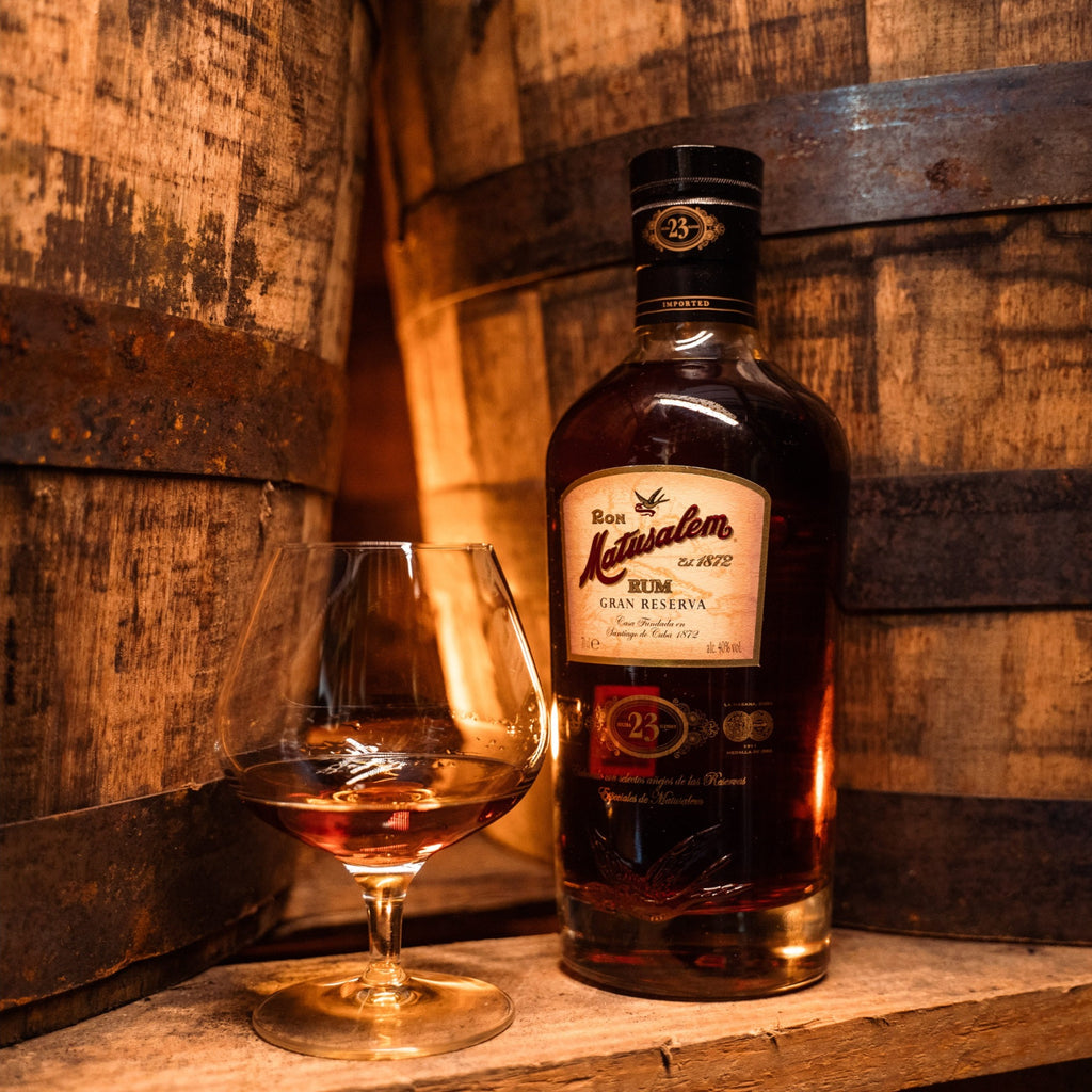 Bottle and glass of 23 year old Matusalem rum on wooden barrels