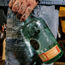 Load image into Gallery viewer, Person holding a Meilli vodka bottle with a label, wearing a denim jacket and pants.