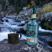 Load image into Gallery viewer, Bottle of Meilli Vodkaand mug on a rock with a natural background