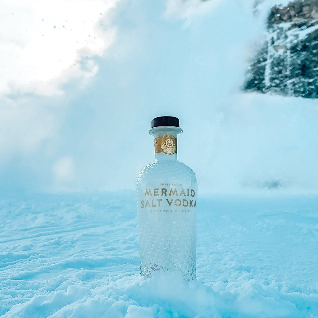 Mermaid Vodka bottle in a snowy landscape with mountains.
