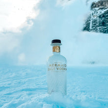 Load image into Gallery viewer, Mermaid Vodka bottle in a snowy landscape with mountains.