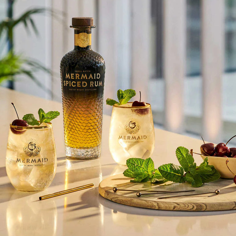 Load image into Gallery viewer, Mermaid Spiced Rum bottle with cocktails and garnishes on a table.