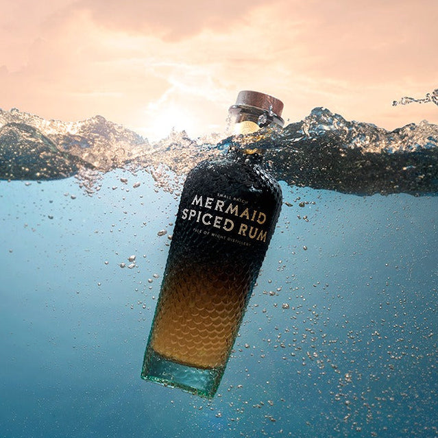 Load image into Gallery viewer, Mermaid Spiced Rum bottle underwater with a sunset sky