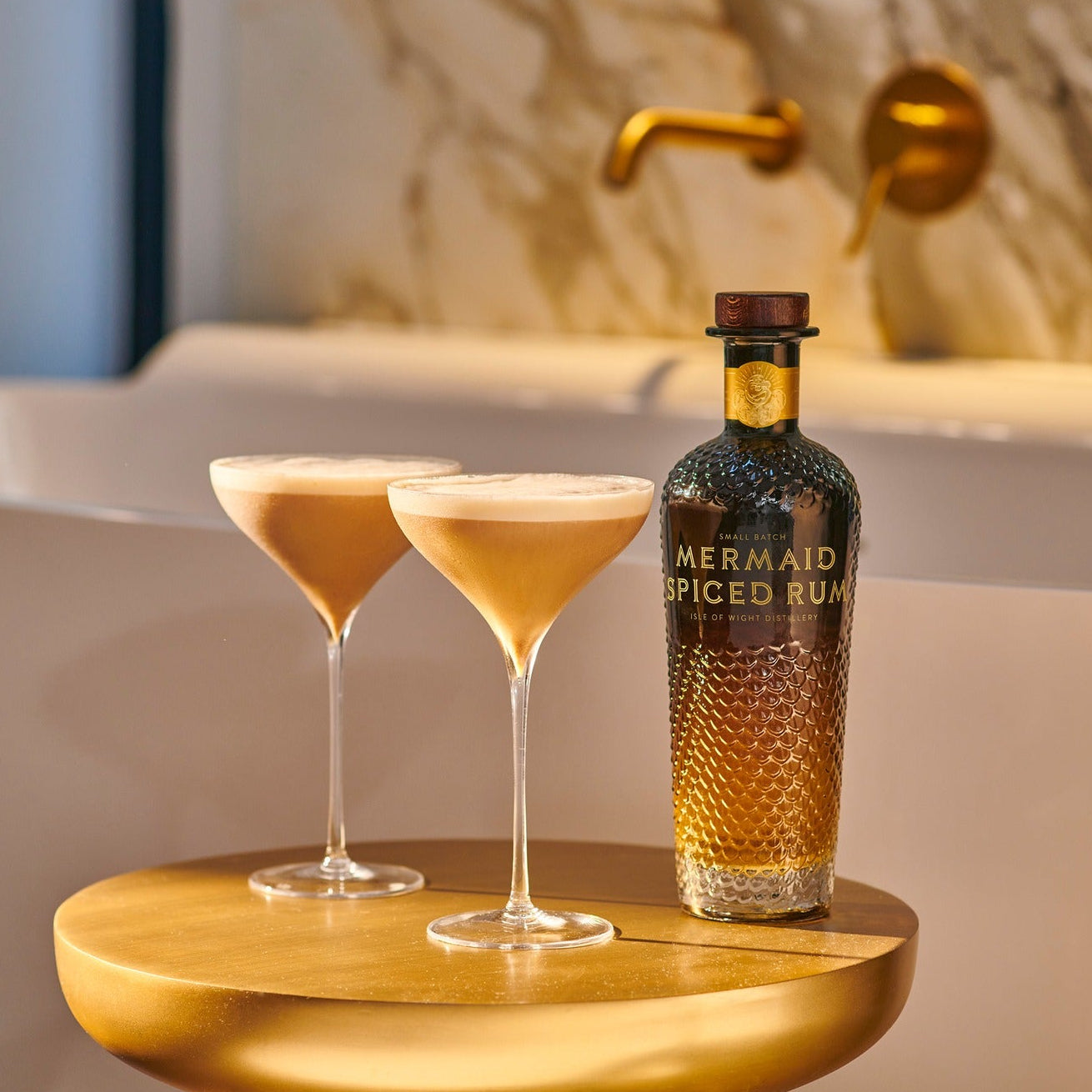 Load image into Gallery viewer, Bottle of Mermaid Spiced Rum with two cocktails on a wooden tray in front of a bathtub.