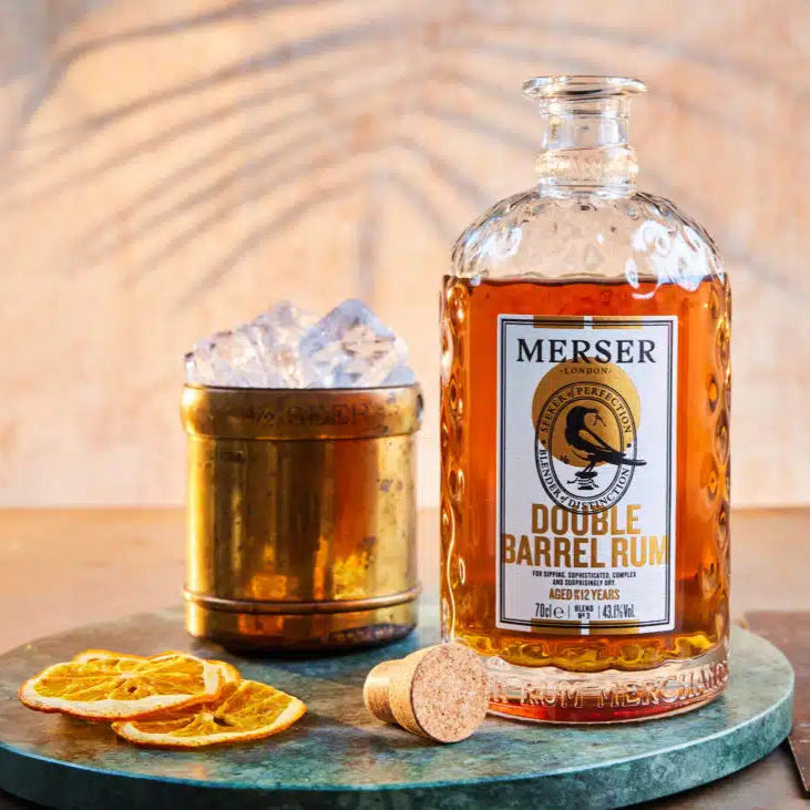 Bottle of Merser Double Barrel Rum with a cocktail on a wooden table