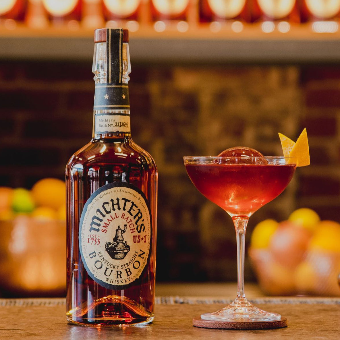 Load image into Gallery viewer, Bottle of Michter's bourbon and a cocktail on a bar with pumpkins in the background.
