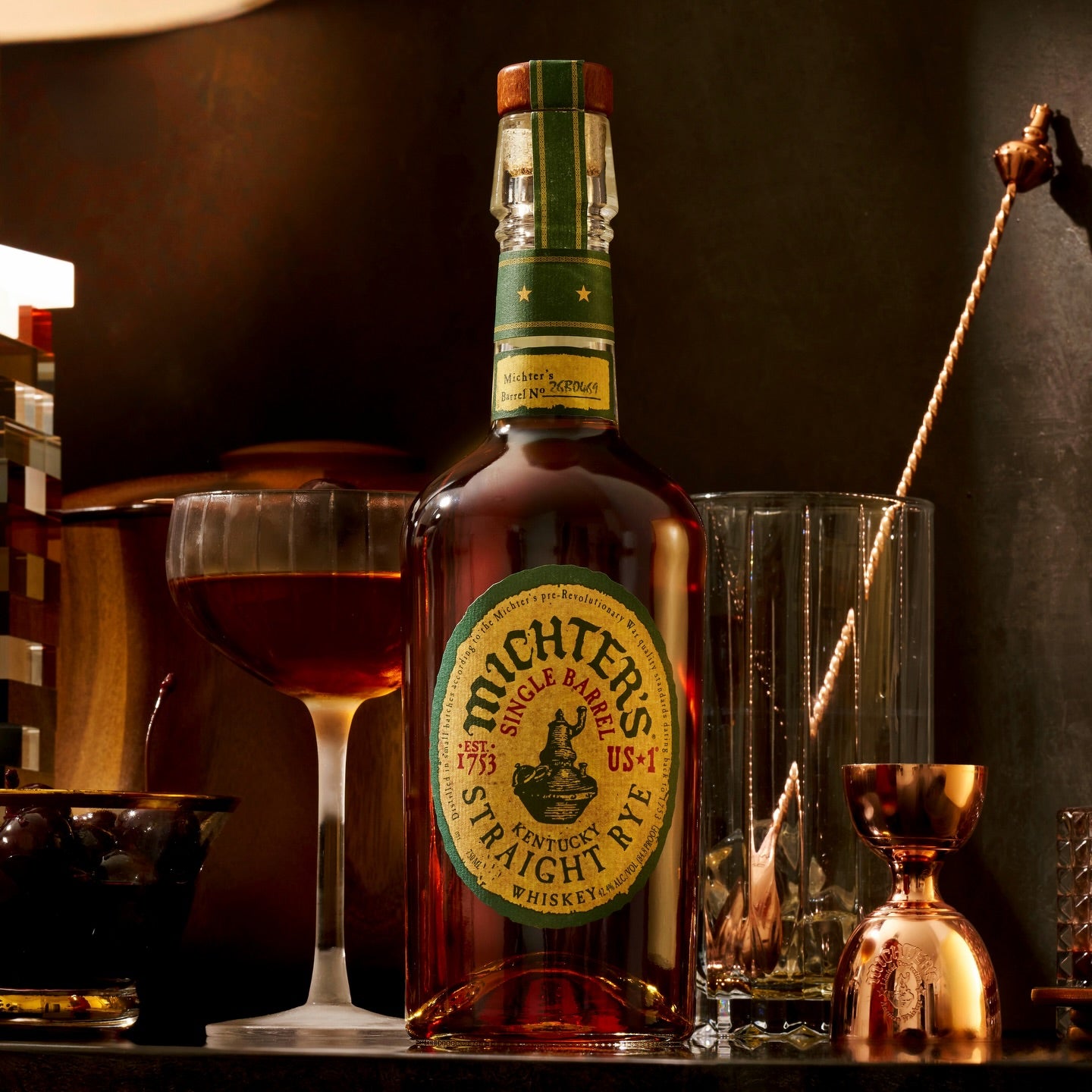 Load image into Gallery viewer, Michter's Michter’s US1 Single Barrel Rye Whiskey bottle with glasses and bar tools on a dark background