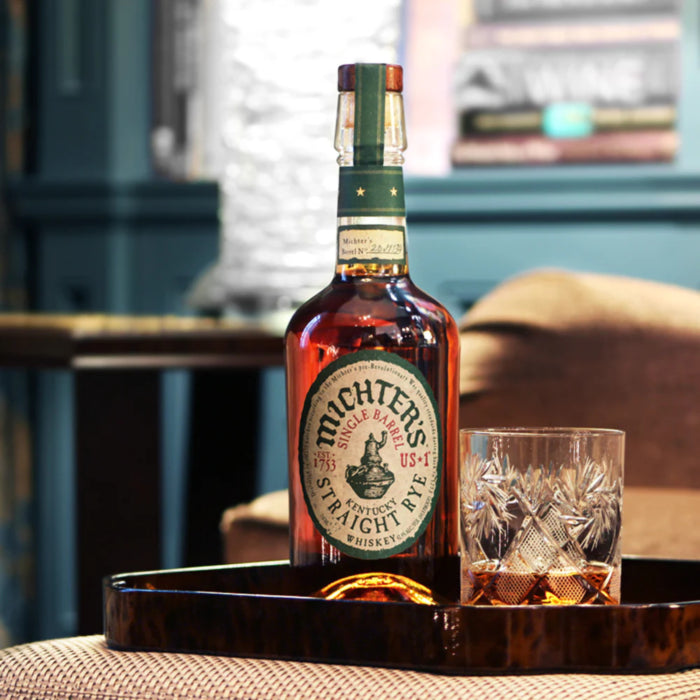 Load image into Gallery viewer, Bottle of Michter's Michter’s US1 Single Barrel Rye Whiskey with a glass on a wooden tray in a cozy room.