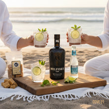Load image into Gallery viewer, Two people enjoying cocktails with Milford Gin on a beach setting.