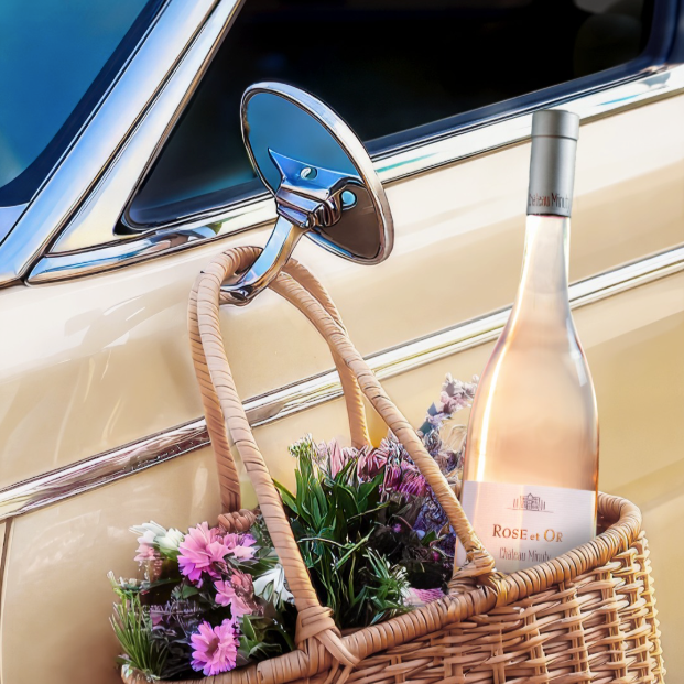 Load image into Gallery viewer, Bottle of Rose et Or rosé wine in a wicker basket with flowers inside a vintage car.