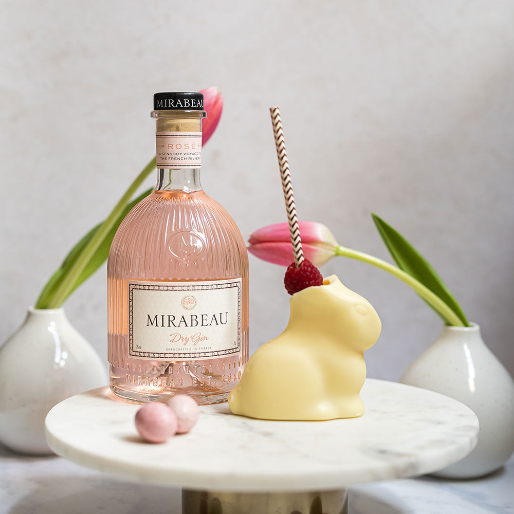 Load image into Gallery viewer, Bottle of Mirabeau Dry Gin with a Easter white chocolate Bunny and tulips on a marble surface.