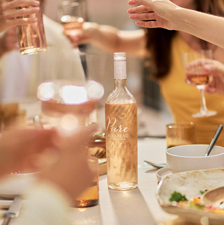 Load image into Gallery viewer, Bottle of Mirabeau Pure Provence Rosé wine on a table with people around