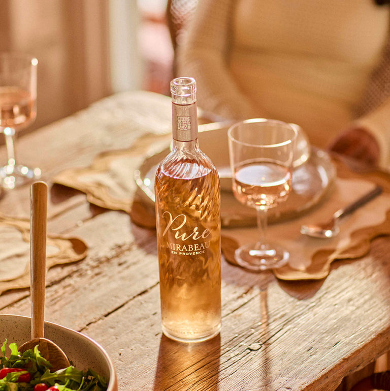 Load image into Gallery viewer, Bottle of Mirabeau Pure Provence Rosé wine on a wooden table with a glass and salad