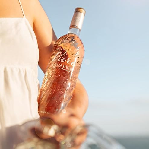 Load image into Gallery viewer, Person holding a bottle of Mirabeau Pure Provence Rosé wine with a blurred background