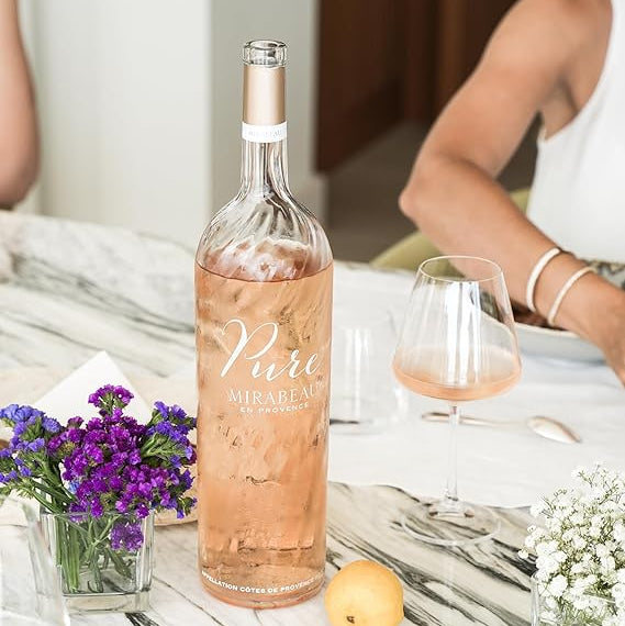 Load image into Gallery viewer, Bottle of Mirabeau Pure Provence Rosé wine on a table with a glass and flowers.