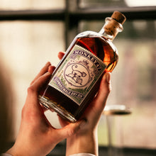 Load image into Gallery viewer, Hand holding a bottle of Monkey 47 gin with a blurred background