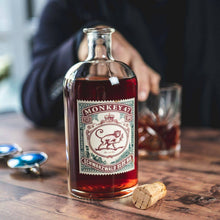 Load image into Gallery viewer, Bottle of Monkey 47 sloe gin on a wooden table with a blurred person in the background.
