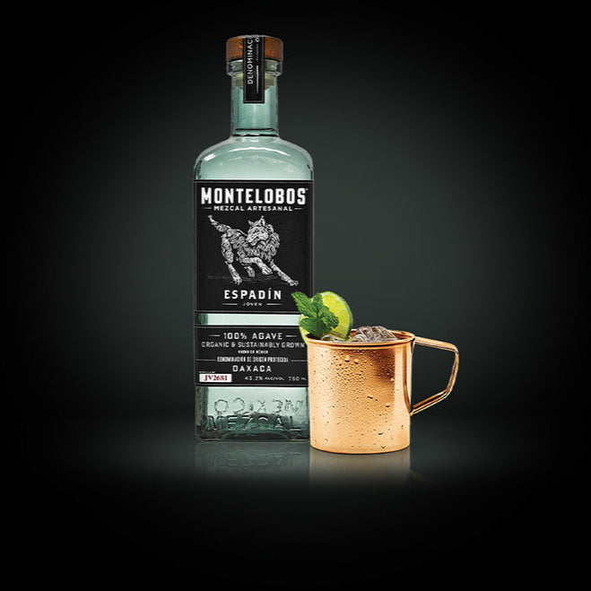 Load image into Gallery viewer, Montelobos Espadin mezcal bottle with a copper mug containing a cocktail on a dark background