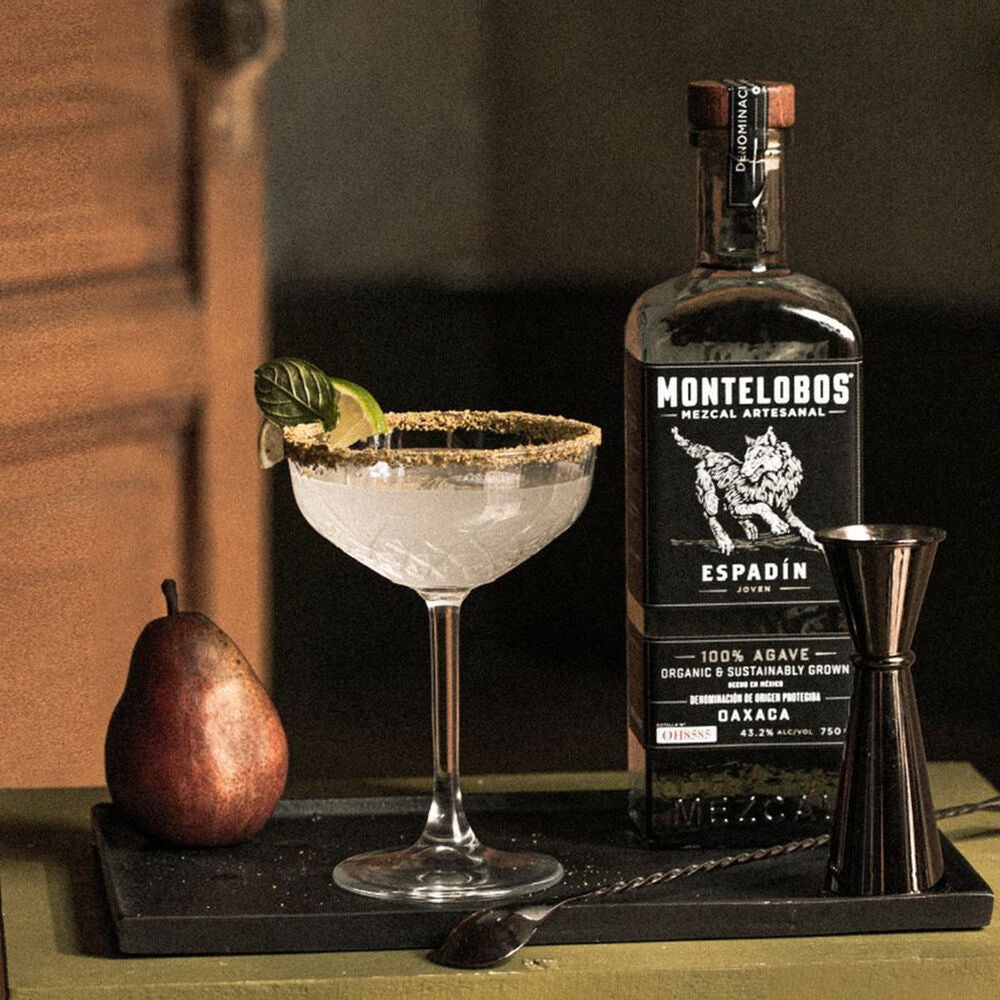 Load image into Gallery viewer, Bottle of Montelobos Espadin mezcal with a cocktail and pear on a tray.