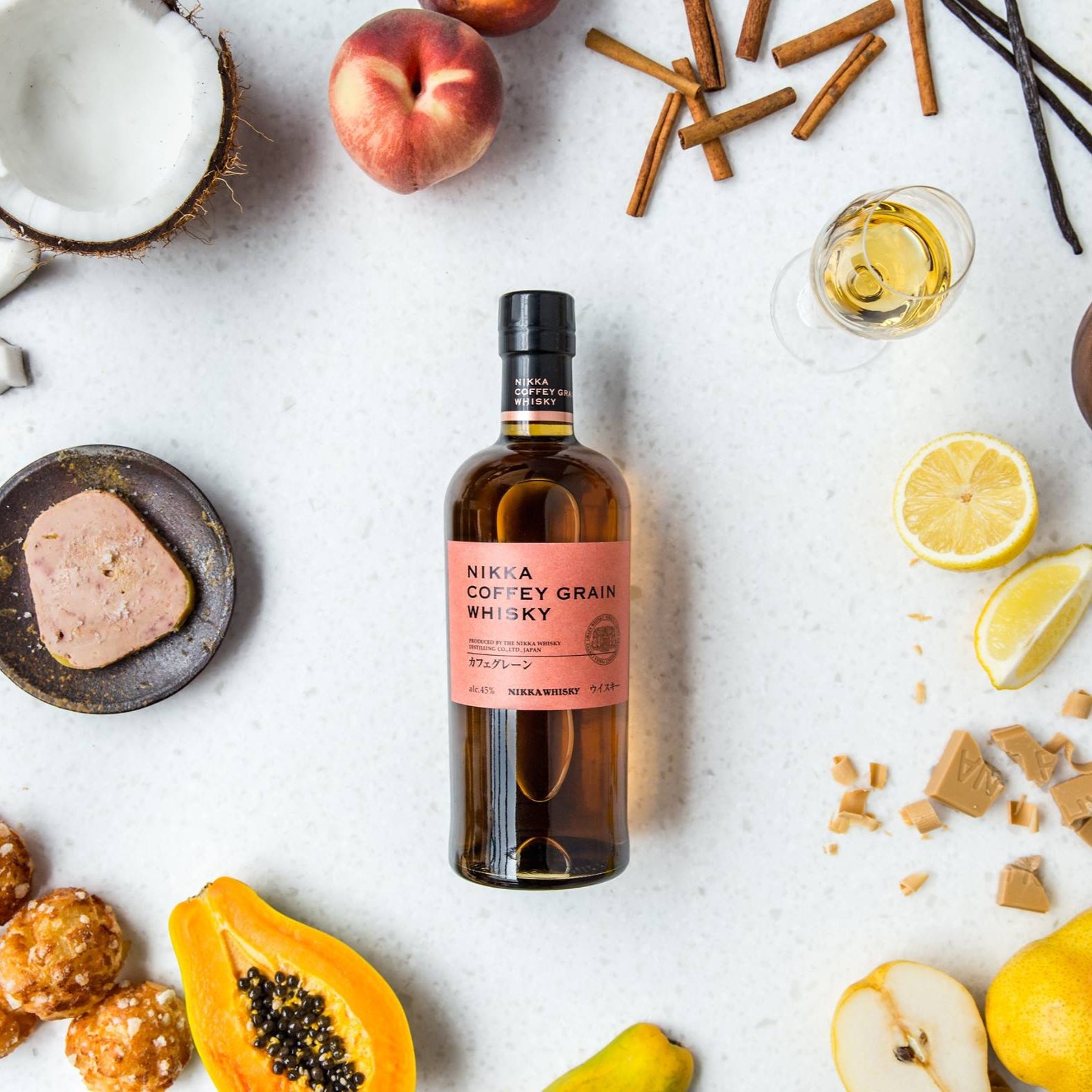 Load image into Gallery viewer, Bottle of whiskey surrounded by fruits and snacks on a white surface