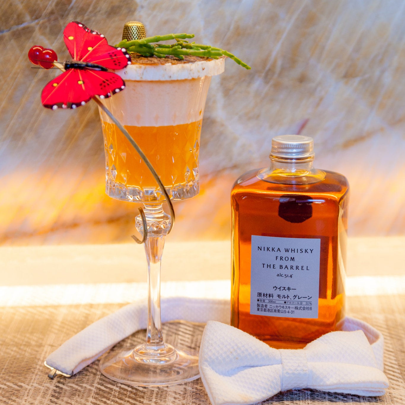 Load image into Gallery viewer, Malt whisky cocktail with butterfly garnish and bottle on woven surface.