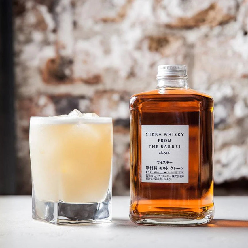 Load image into Gallery viewer, Whisky bottle with a cocktail in a glass against a textured wall.