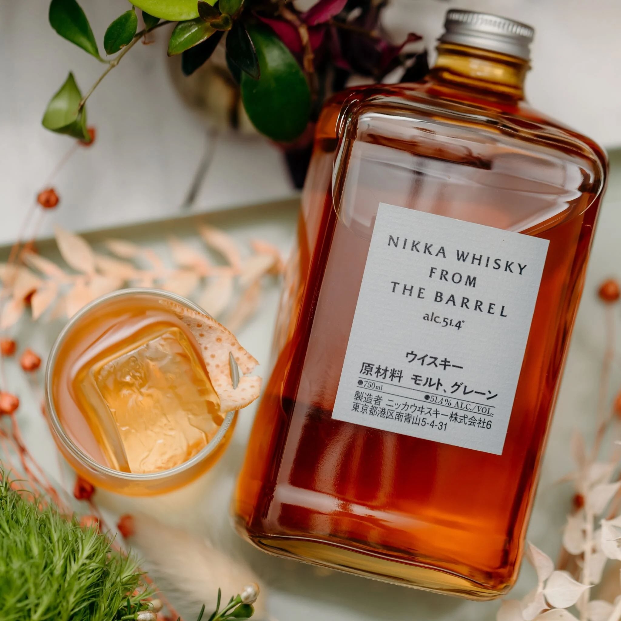 Load image into Gallery viewer, Nikka Whisky bottle with a cocktail and decorative plants.