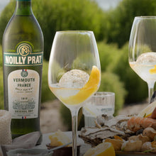 Load image into Gallery viewer, Noilly Prat Original Dry Vermouth bottle with two glasses of Vermouth on a table outdoors.