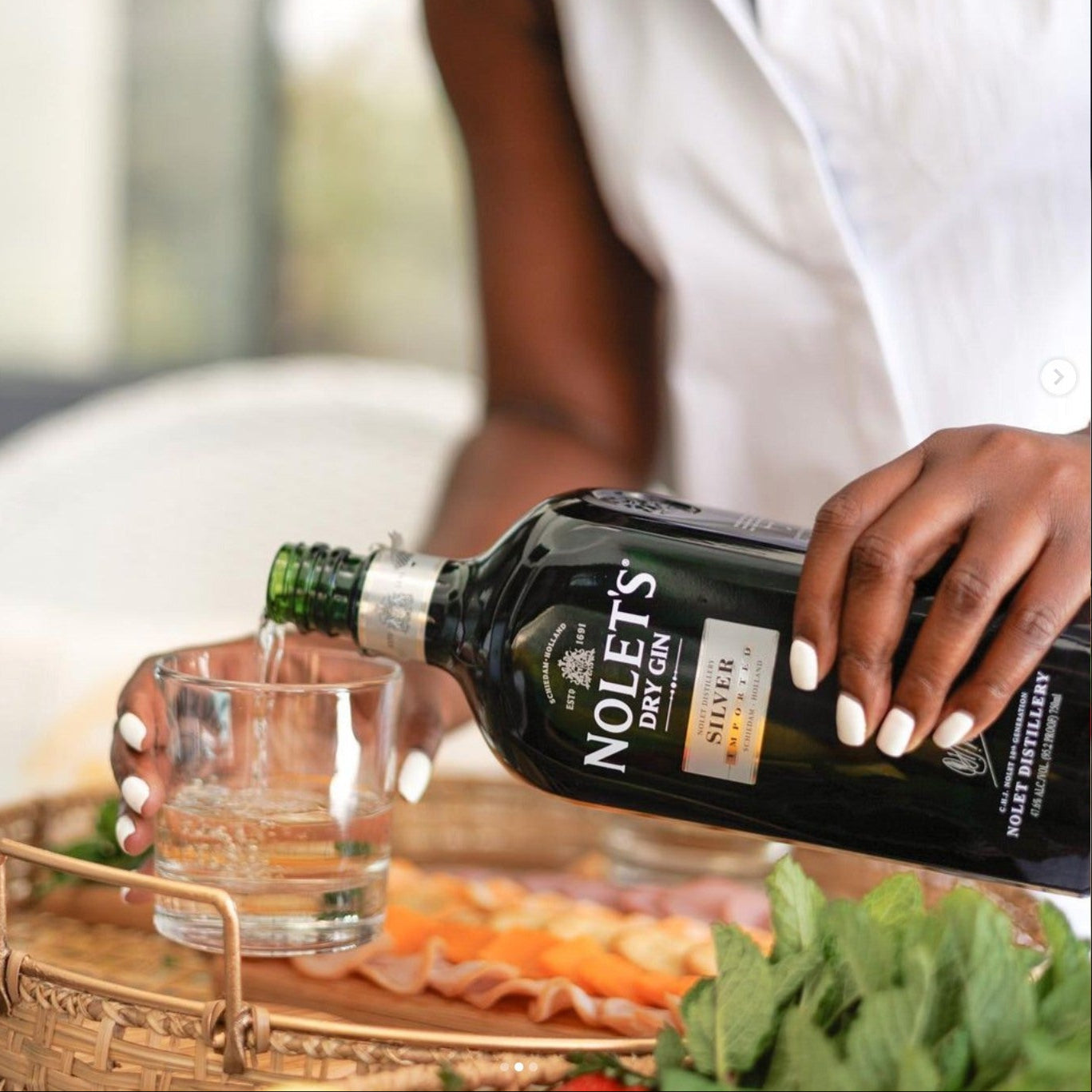 Load image into Gallery viewer, Person pouring Noleth's Dry Gin into a glass with a blurred background