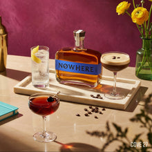 Load image into Gallery viewer, Nowhere BOURBON bottle with cocktails and flowers on a table