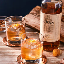 Load image into Gallery viewer, Oban 14-year-old whisky bottle with two glasses of whiskey on a wooden surface.