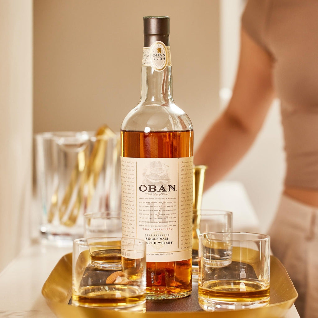 OBAN 14 year old whiskey bottle with two glasses on a gold tray, blurred background