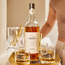 Load image into Gallery viewer, OBAN 14 year old whiskey bottle with two glasses on a gold tray, blurred background